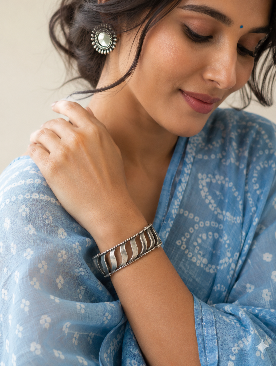 Woman wearing a blue saree with a close-up of her hand and jewelry.