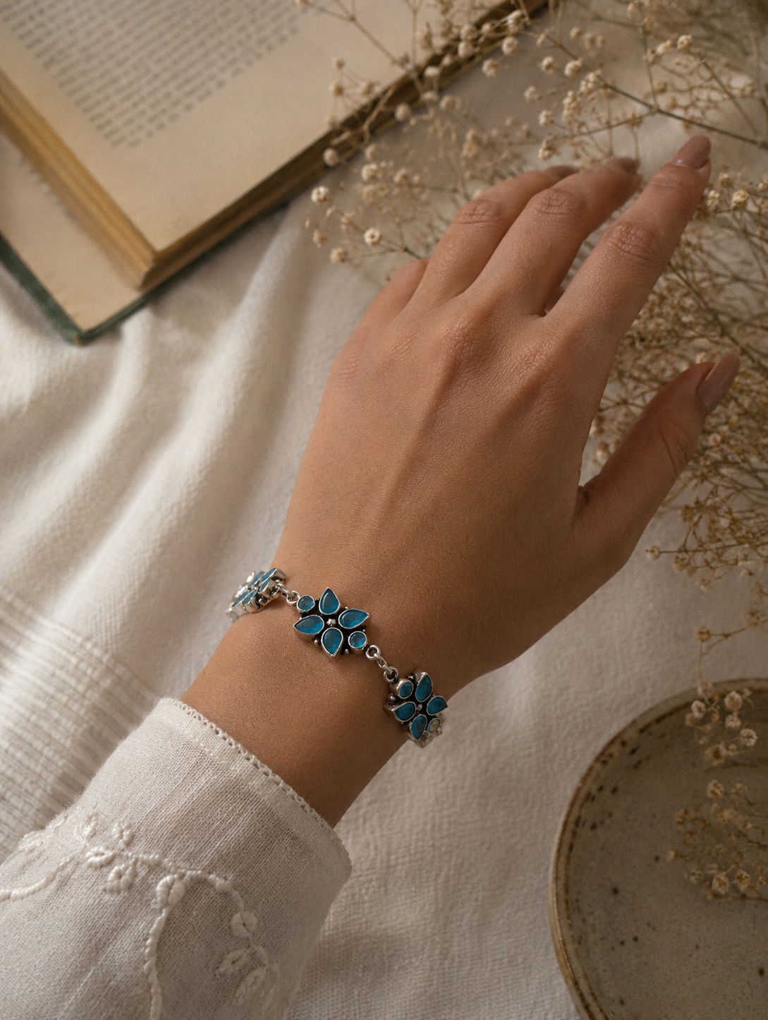An oxidized silver link bracelet featuring three floral clusters made of teardrop-shaped blue stones