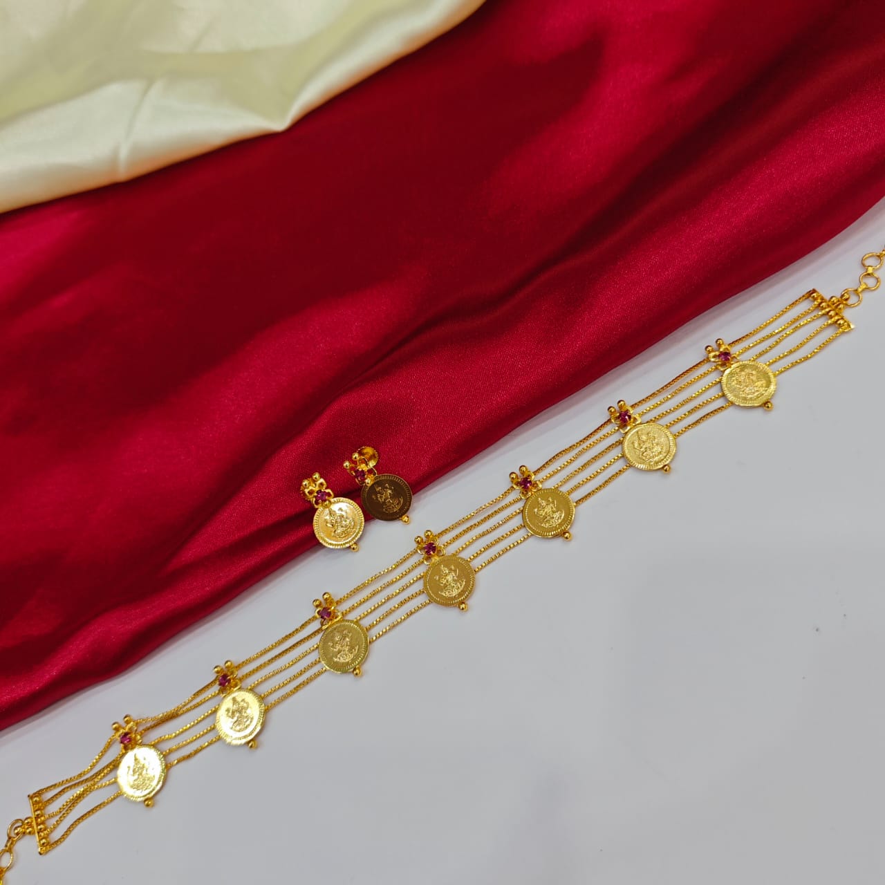 Gold necklace with coins on a red and white fabric background