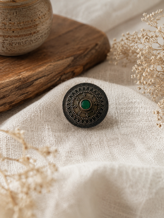 Decorative hair pin with green gemstone on a textured fabric surface