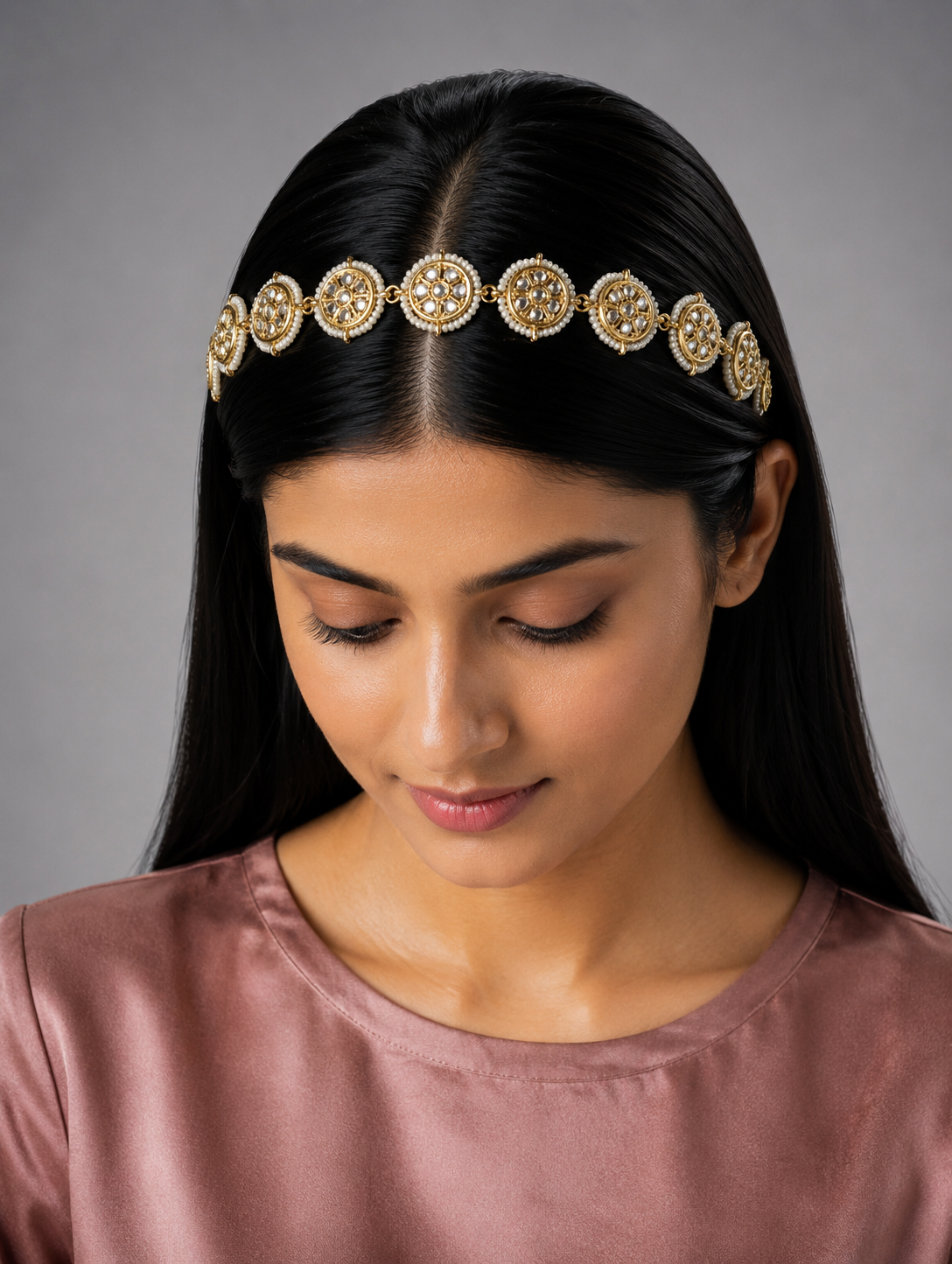 Traditional gold-plated Indian sheeshphool hair accessory featuring a flexible row of circular wheel motifs studded with Kundan stones and framed by tiny white pearls, elegantly displayed against a rich burgundy velvet backdrop.