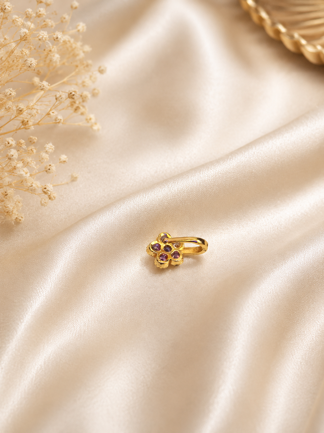 Rear view of the SP016 non-piercing flower nose pin resting on soft cream satin fabric, highlighting the smooth gold-plated adjustable press-fit clip mechanism.