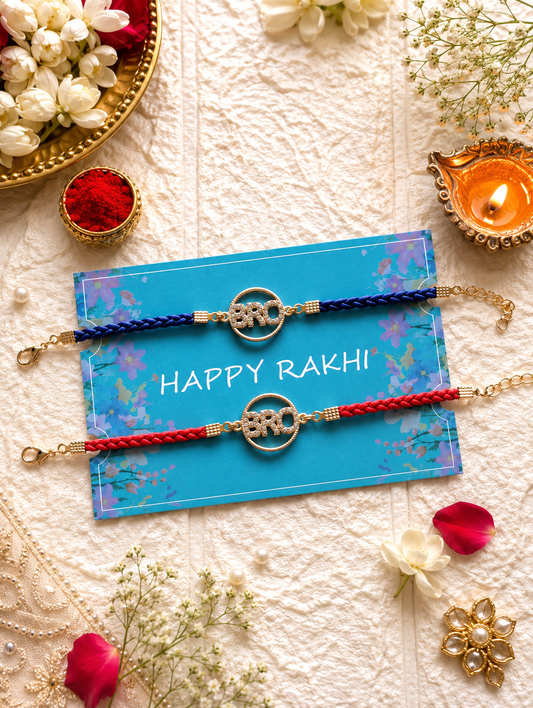 Set of two stone-studded 'BRO' circular emblem Rakhi bracelets in royal blue and red braided threads on a blue Happy Rakhi greeting card.