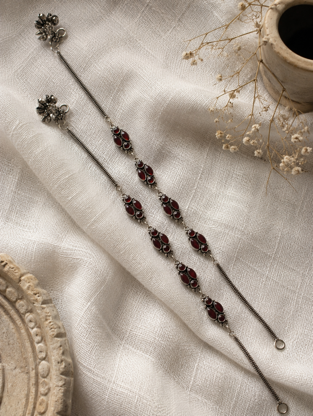 Decorative hairpin with maroon stones on a textured beige fabric background