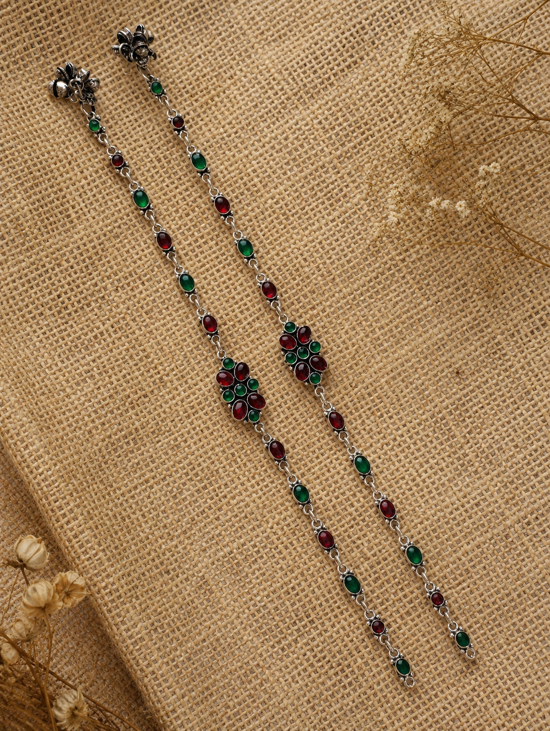 Decorative chain with red and green beads on a textured beige background