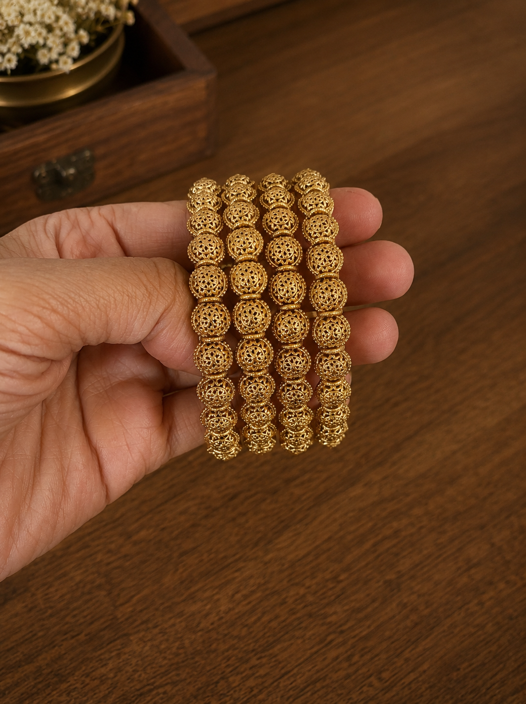 Gold bracelet on a hand with a wooden background