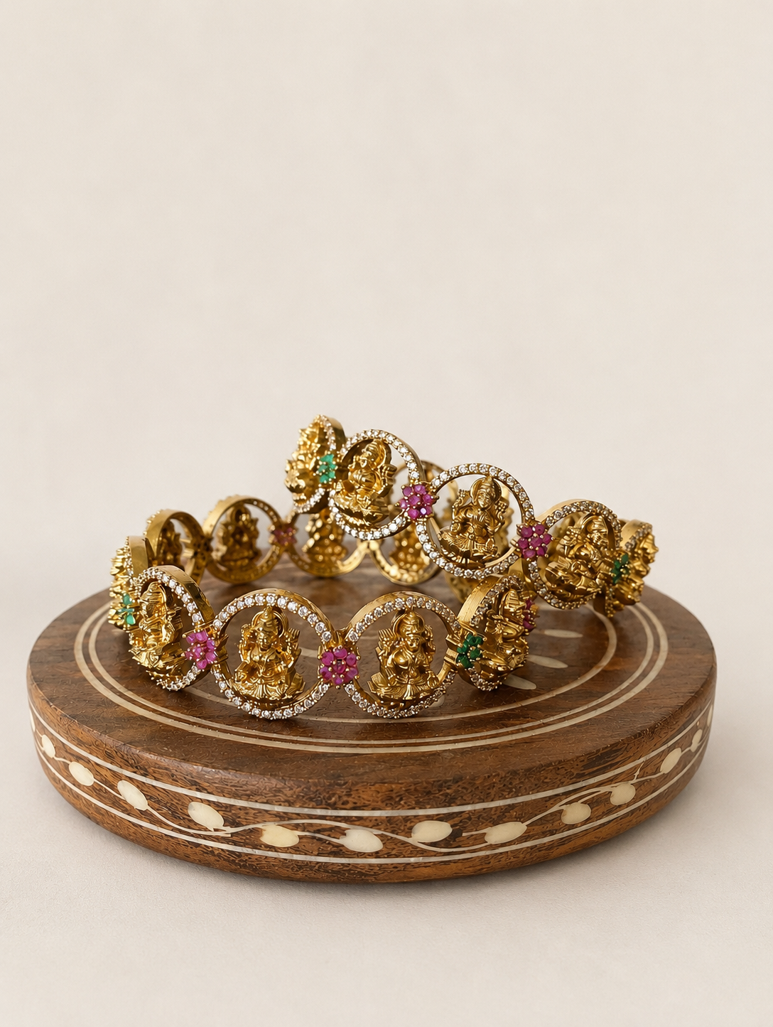 Gold jewelry set on a wooden stand with a beige background