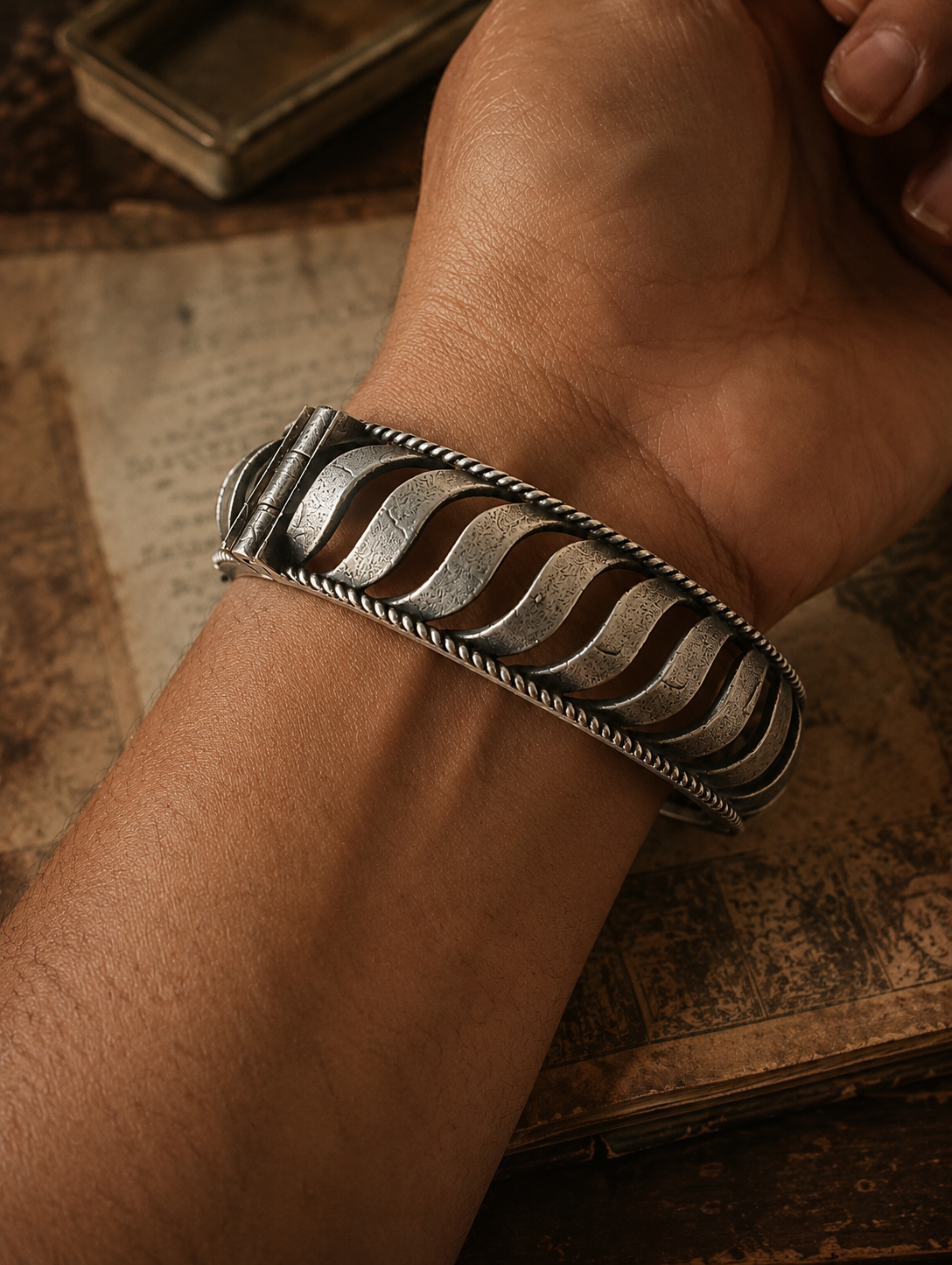Silver bracelet with wavy pattern on a wrist against an old book background