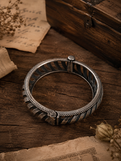 Silver bracelet on a wooden surface with dried flowers and an old book