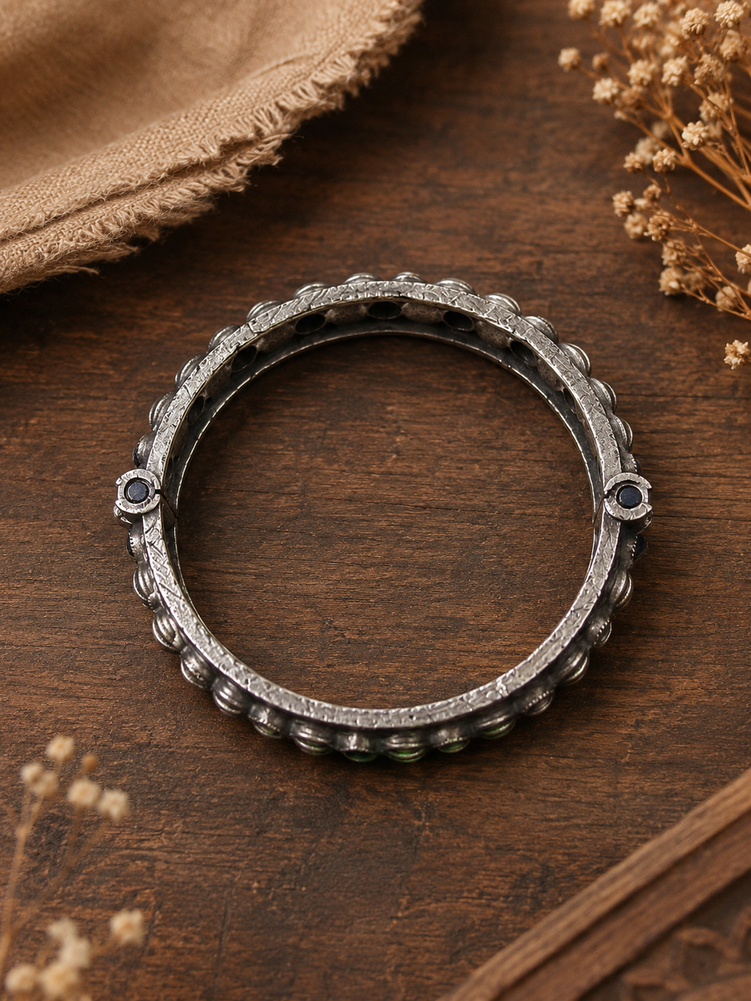 Silver ring with embedded stones on a wooden surface