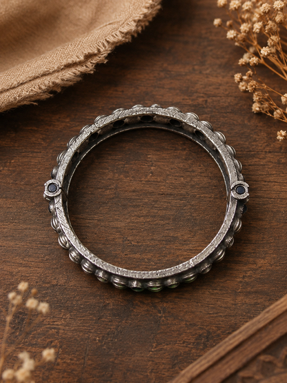 Silver ring with embedded stones on a wooden surface