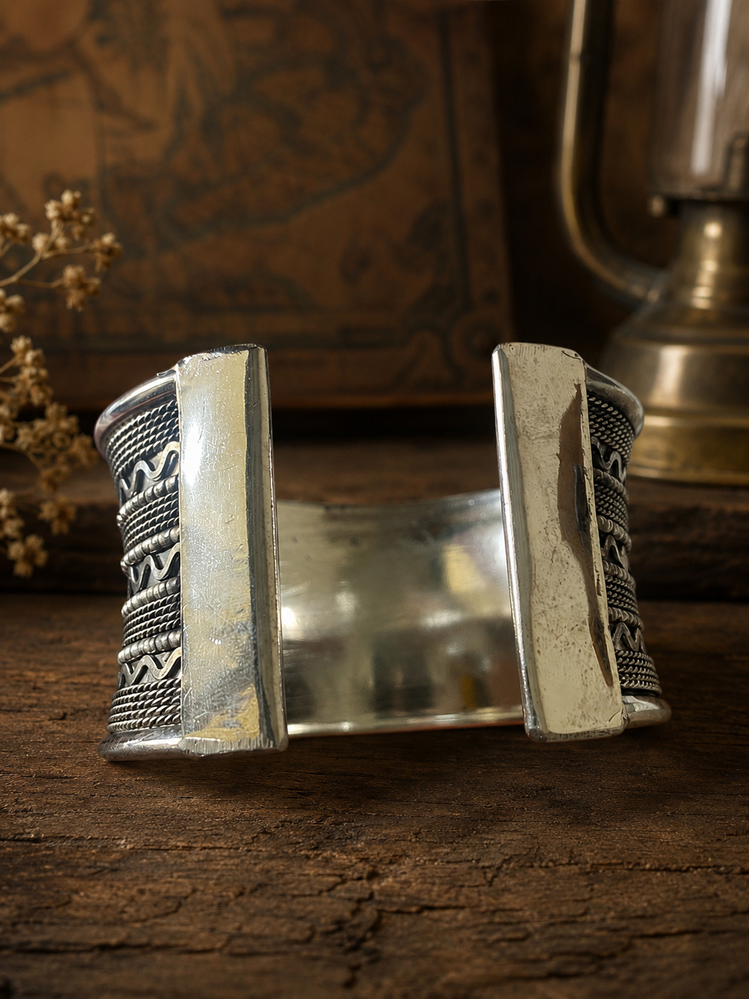 Silver bracelet with intricate patterns on a wooden surface