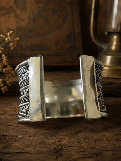 Silver bracelet with intricate patterns on a wooden surface