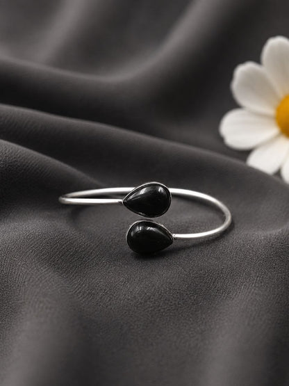 Silver ring with black stones on a dark fabric background