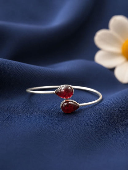 Silver bracelet with red gemstones on a blue fabric background