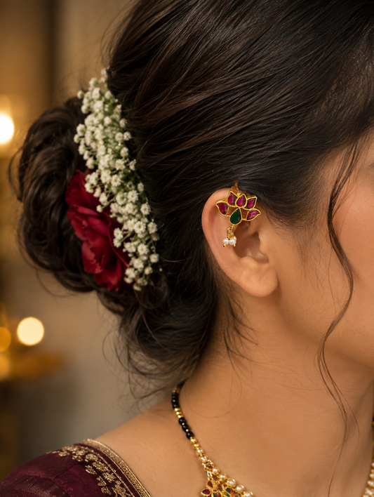 Side profile of a woman wearing a traditional gold Lotus Jadau Kundan Bugudi ear cuff on her upper ear cartilage, styled alongside an elegant hair bun decorated with white flowers and a red rose.