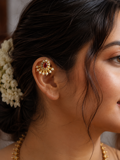 Side view of a woman wearing the traditional gold-plated Ruby Pearl Buggudi ear cuff on her upper helix, styled with a traditional gajra in her hair.