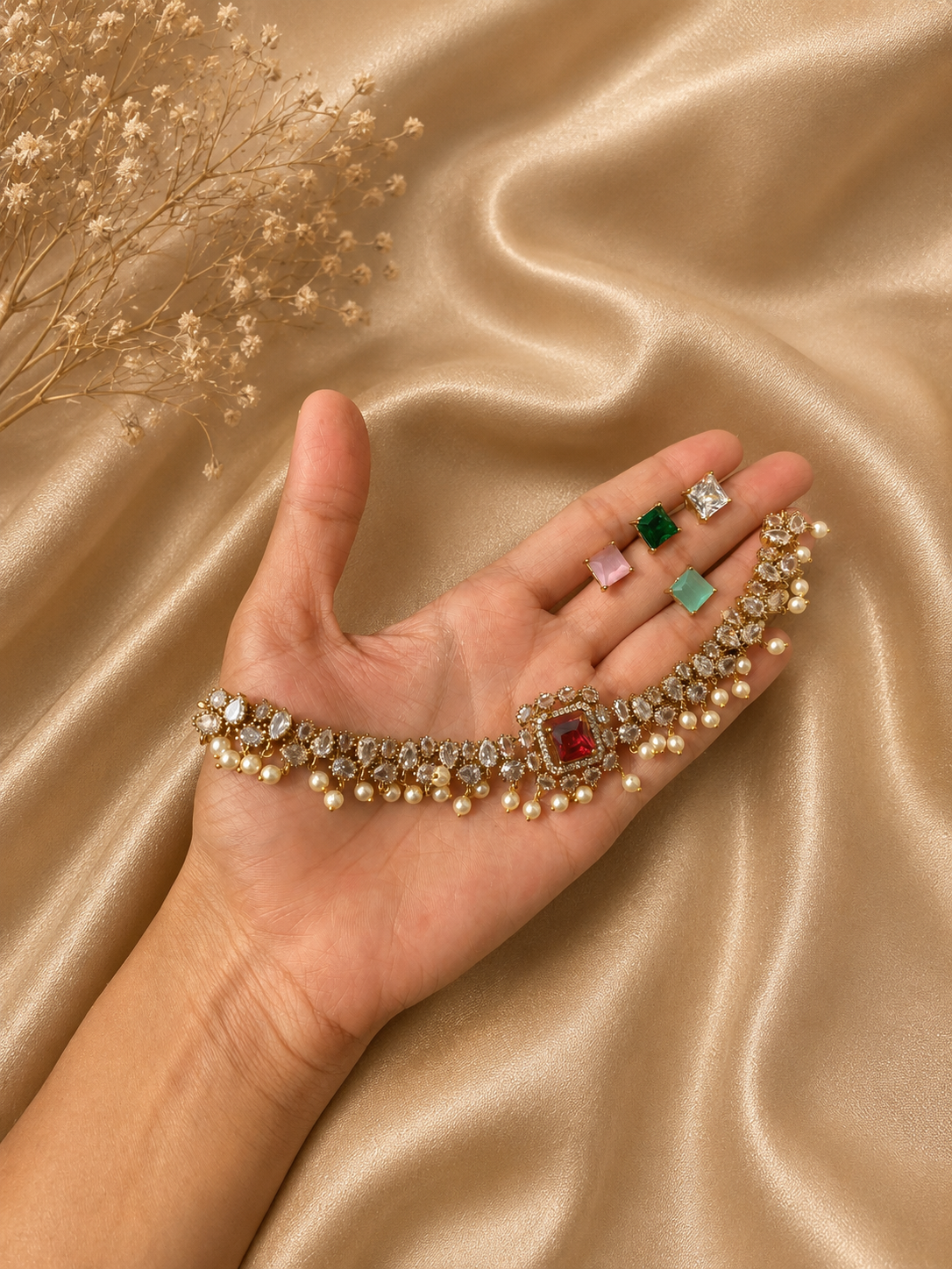 Hand holding a bracelet with various gemstones on a gold fabric background