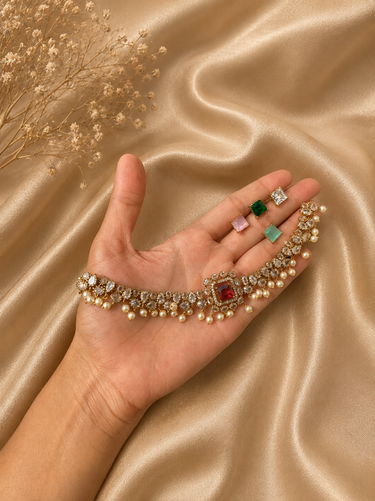 Hand holding a bracelet with various gemstones on a gold fabric background