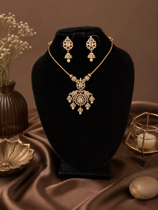 Gold necklace and earrings set on a black velvet stand with a brown fabric background