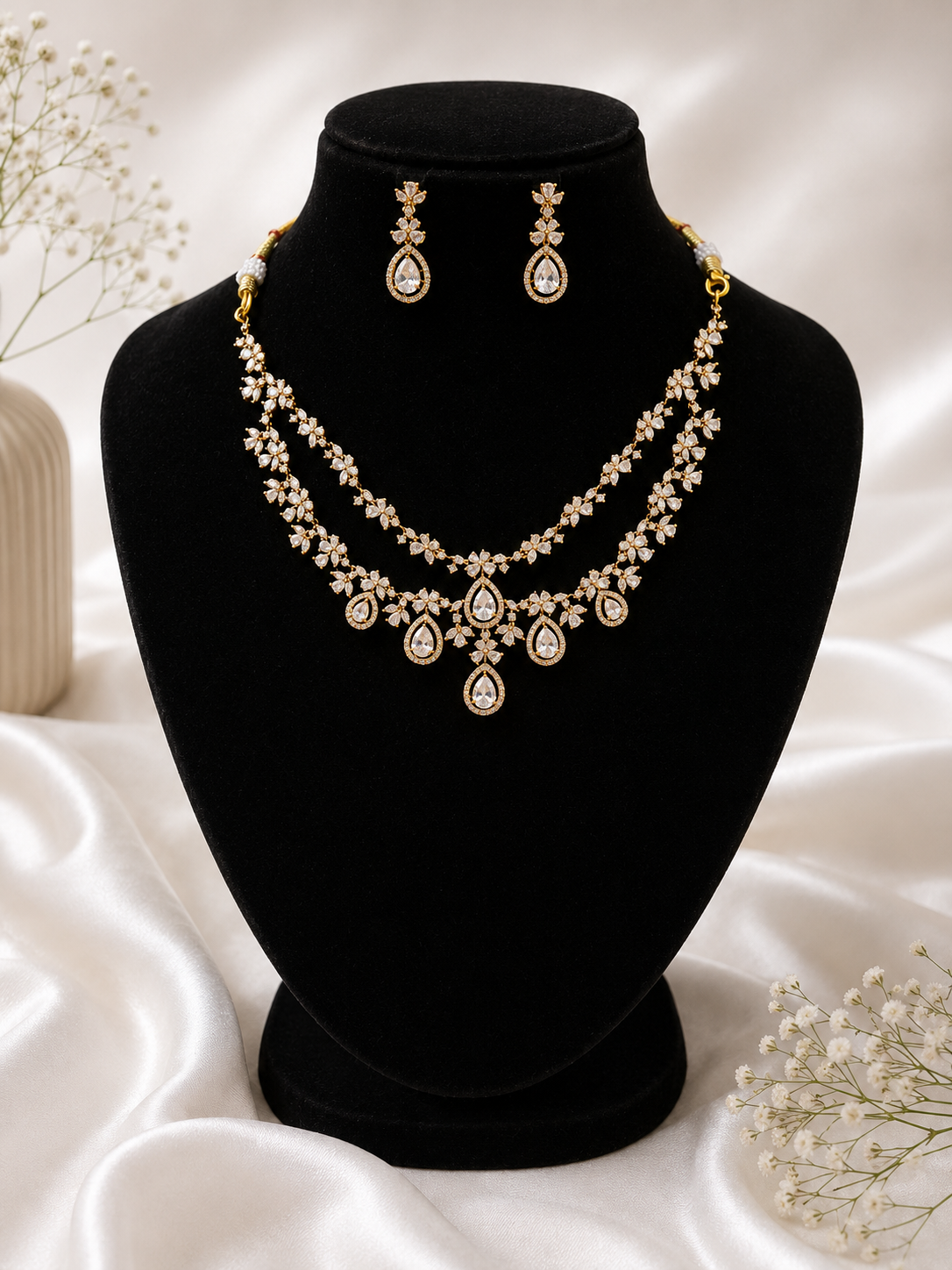 Jewelry set with necklace and earrings on a black mannequin bust against a white background.