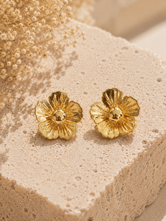 Celebrate the beauty of nature with a luxurious, high-fashion statement in our striking Gold Flora Stud Earrings. These oversized button studs feature a beautifully rendered five-petal blossom design, complete with a prominent, smooth dome center. The petals are meticulously sculpted with a fine, radial fluted texture that replicates the intricate veining of real wild blooms.

Finished in a premium, ultra-glossy liquid gold polish, the deep ridges on each petal capture the natural sunlight with breathtaking