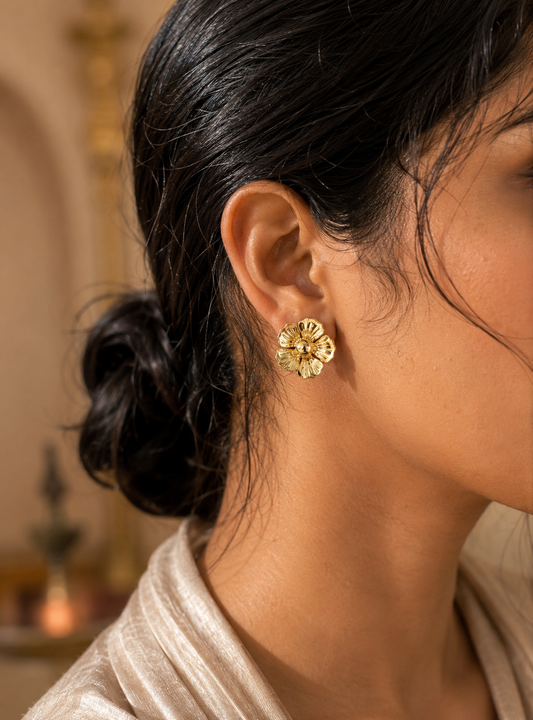 Celebrate the beauty of nature with a luxurious, high-fashion statement in our striking Gold Flora Stud Earrings. These oversized button studs feature a beautifully rendered five-petal blossom design, complete with a prominent, smooth dome center. The petals are meticulously sculpted with a fine, radial fluted texture that replicates the intricate veining of real wild blooms.

Finished in a premium, ultra-glossy liquid gold polish, the deep ridges on each petal capture the natural sunlight with breathtaking
