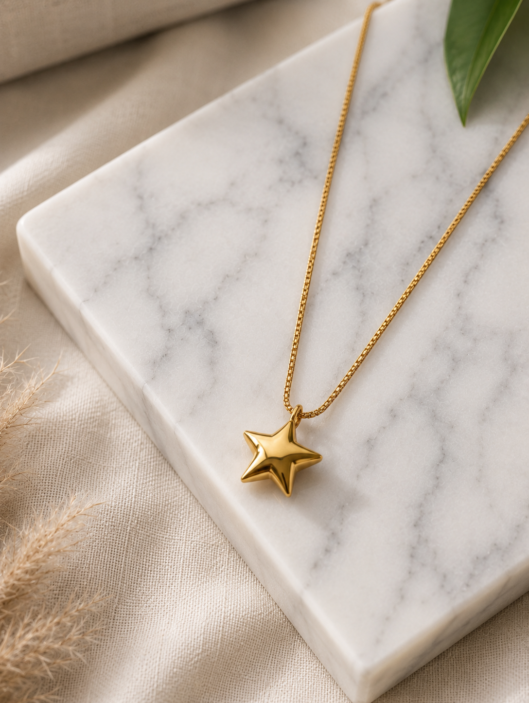 Here is a comprehensive, one-paragraph alt text for **GN016_star chain.png**, balancing descriptive detail with conciseness for an e-commerce or catalog setting:

> A close-up photograph focusing on a woman's neck and collarbone, highlighting a minimalist gold necklace. The piece features a delicate, thin gold chain carrying a polished, three-dimensional five-pointed star pendant that rests flat against her skin. The model, showing her jawline, soft dark updos, and a cream strapless top, is captured in warm