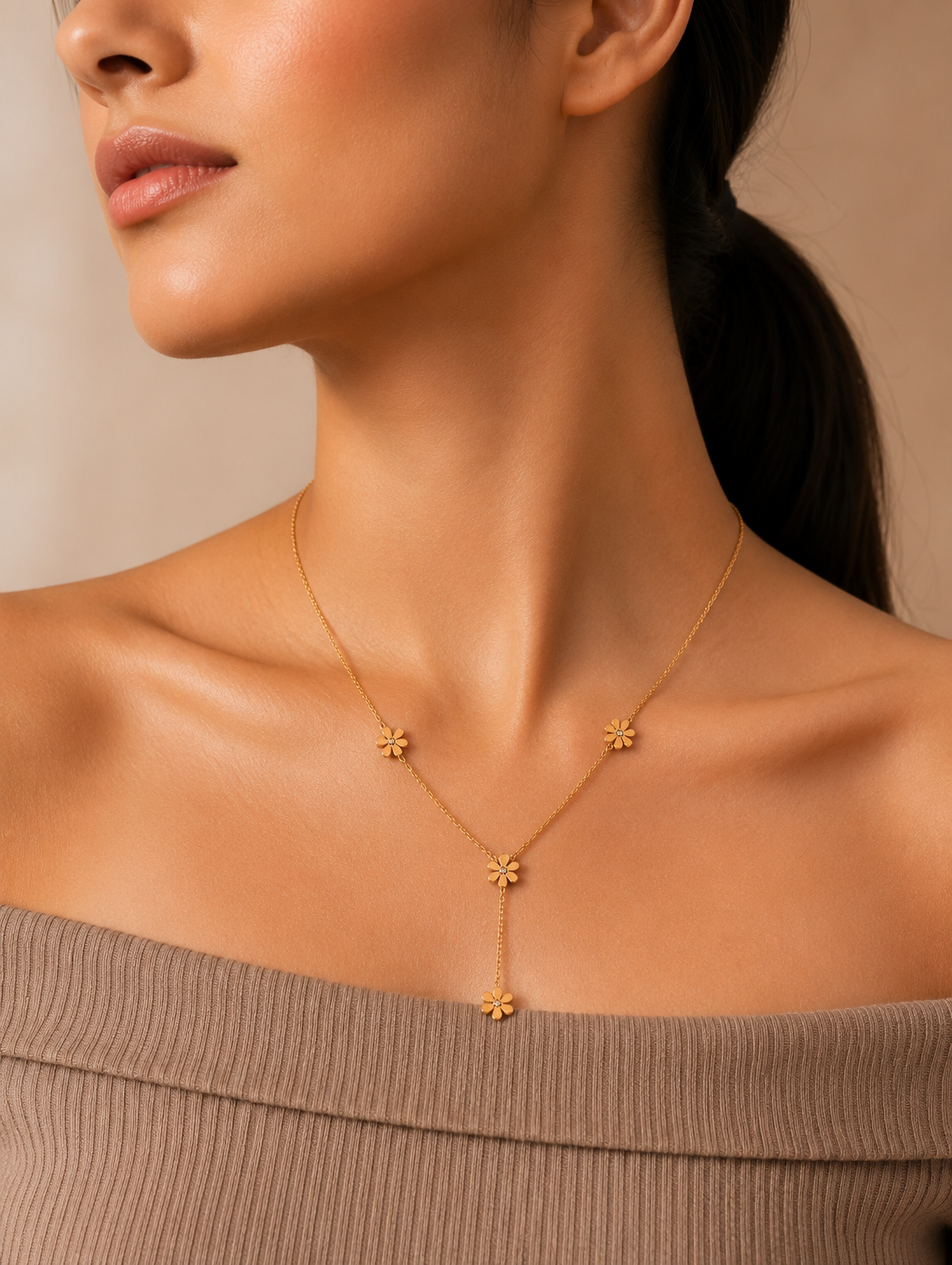 A gold-toned Y-necklace featuring spaced daisy flower stations, each accented with a central crystal. The necklace is showcased through a mix of lifestyle and product photography, including a marble flat lay and a model shot.