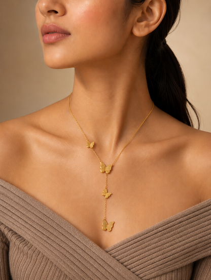 A collection of three product photographs showcasing a delicate gold-tone Y-lariat chain necklace with four cascading, intricately textured butterfly charms, featured as a flat lay on marble (**GN027_butterfly chain.png**), on a velvet display bust (**GN027_butterfly chain_350.png**), and modeled on a woman's neckline (**GN027_butterfly chain_a.png**).