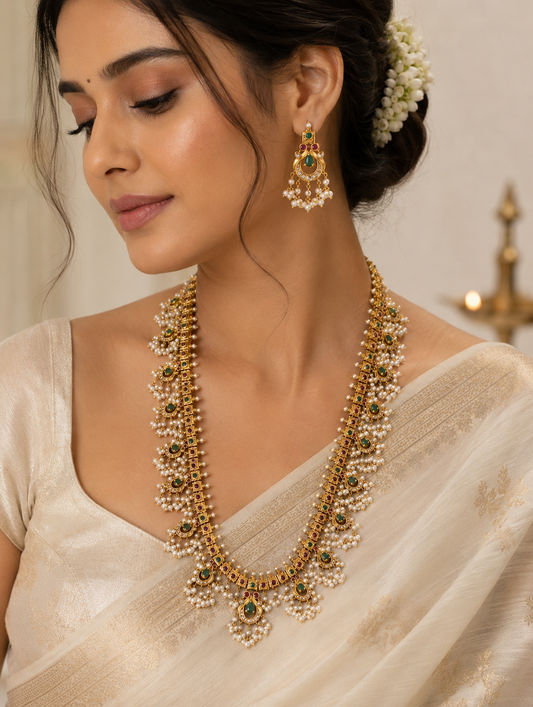 Close-up of a model wearing the Jayanthi Traditional Guttapusalu long haram set paired with a classic off-white silk saree, highlighting the matching earrings and intricate South Indian bridal jewelry design.