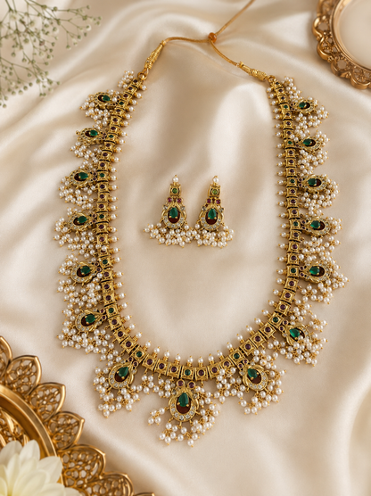 Gold necklace with pearls and green gemstones on a beige fabric background