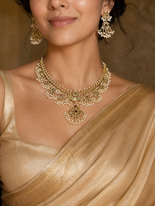 Close-up of a model wearing the Bhavishya Guttapusalu necklace set with matching earrings, perfectly styled with a shimmering gold silk saree for a classic bridal look.