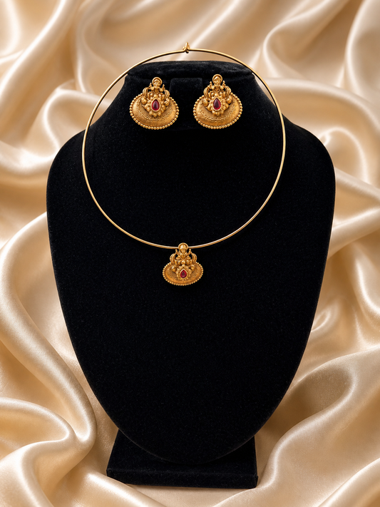 Gold necklace and earrings set on a black velvet stand with a beige satin background