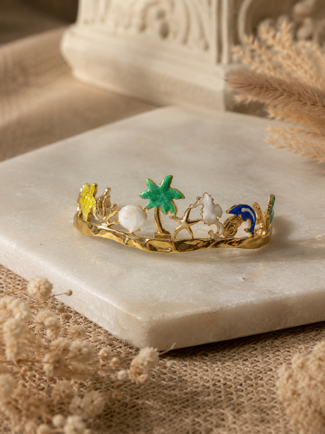 Decorative ring with palm tree and beach scene design on a marble surface.