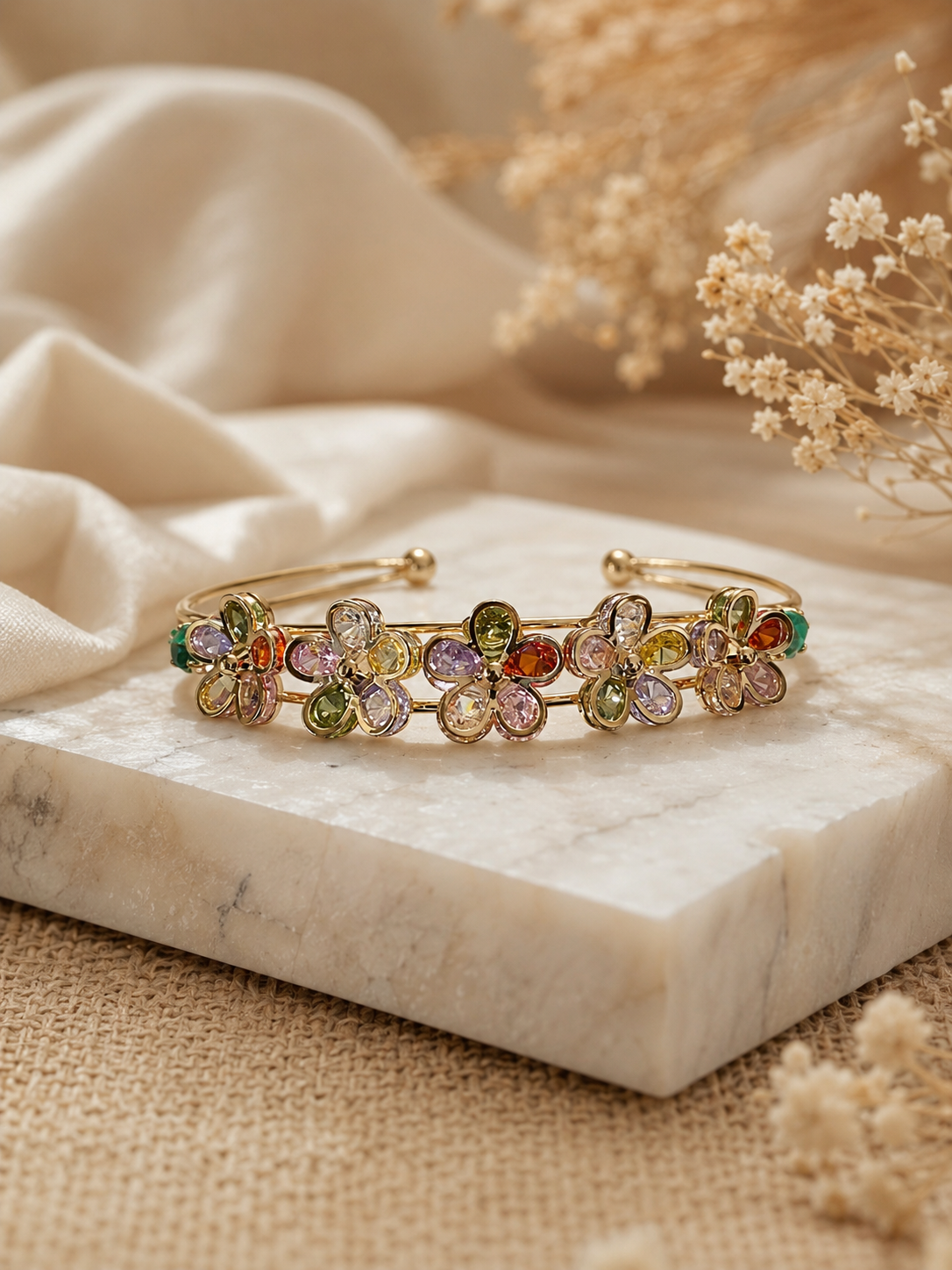 Multicolored floral bracelet on a marble surface with dried flowers in the background