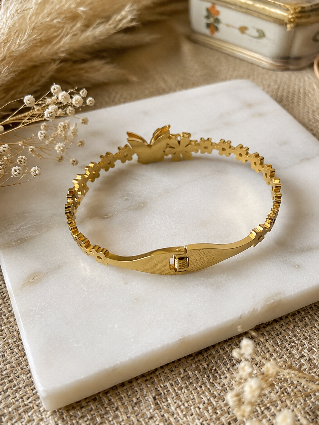 Gold bracelet on a marble surface with decorative elements