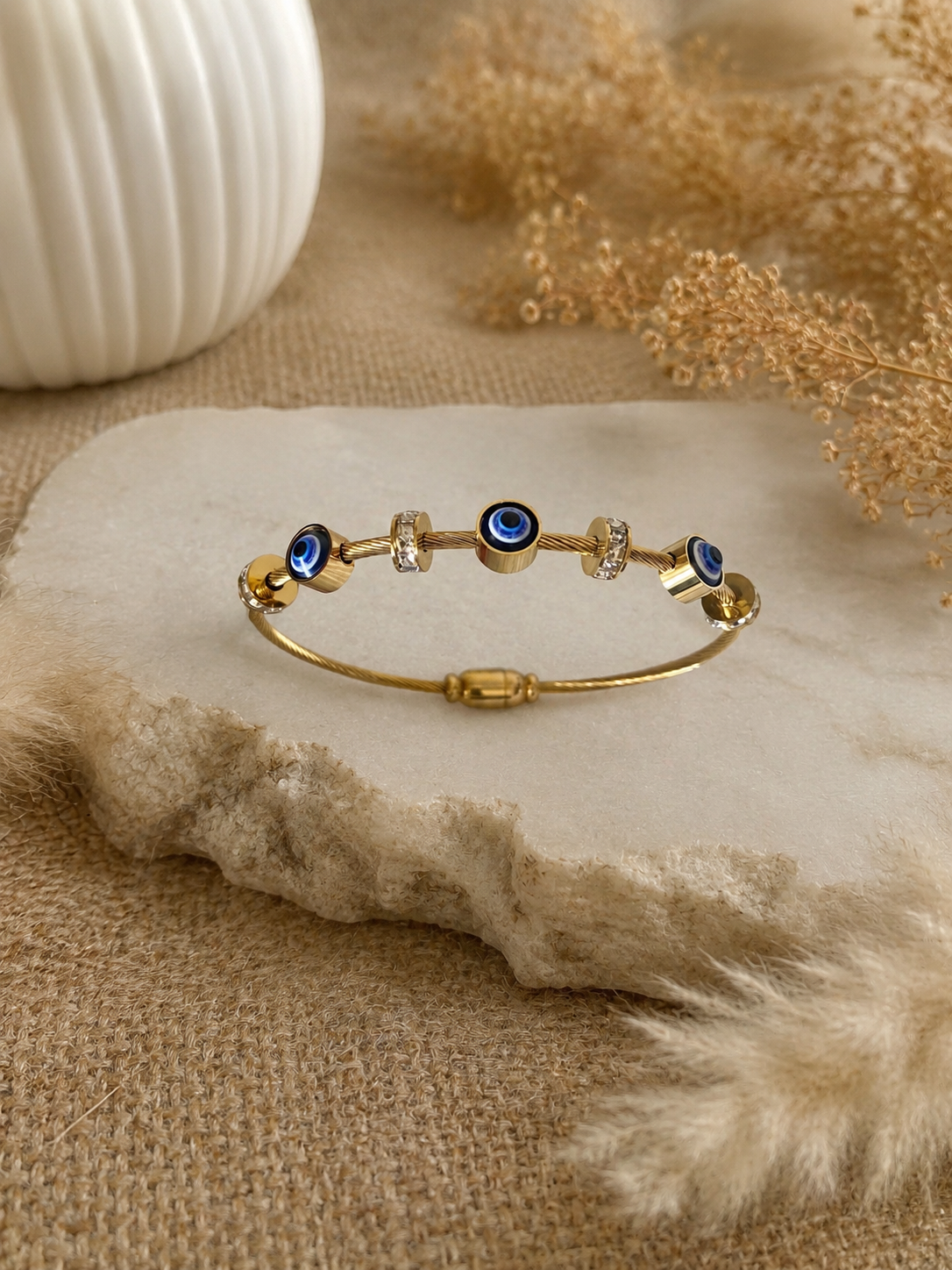 Gold bracelet with blue and clear stones on a textured beige surface