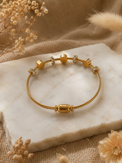 Gold bracelet on a marble surface with dried flowers