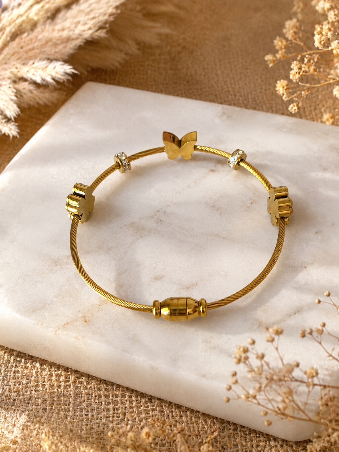Gold bracelet on a marble surface with a natural background