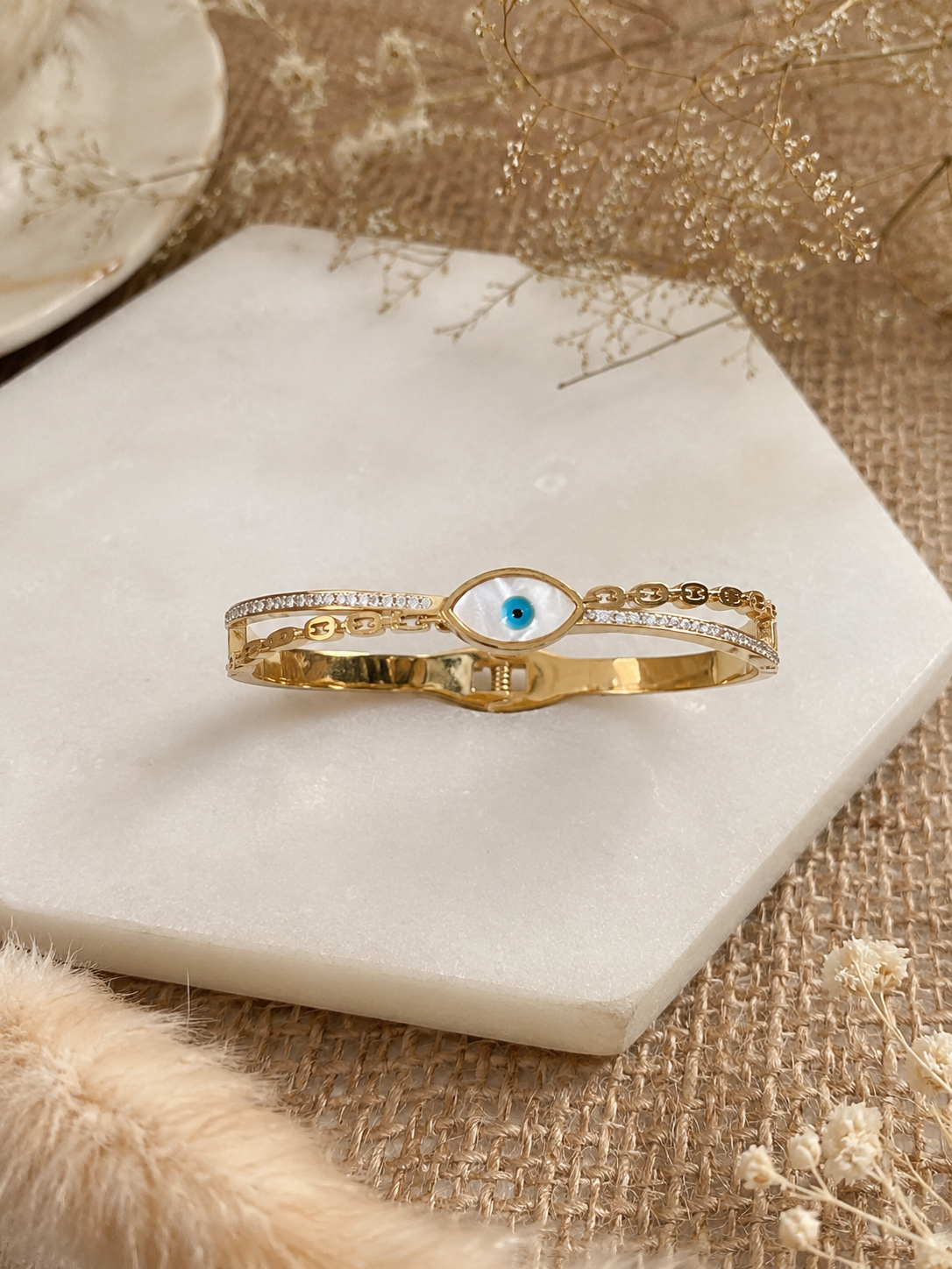 Gold bracelet with an eye design on a marble surface