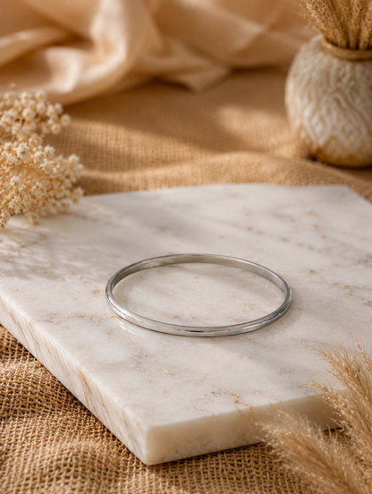 Antica Designs premium silver-toned minimalist kada bracelet with a polished central ridge, displayed flat on a white veined marble slab
