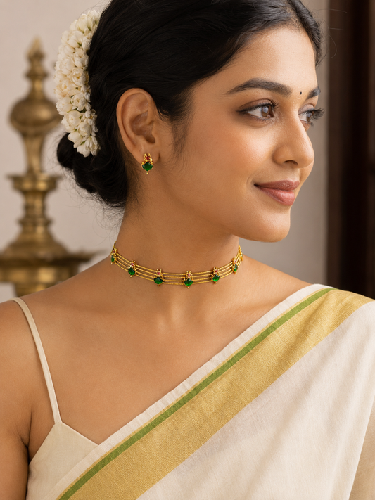 Woman wearing a gold and green necklace with a blurred background