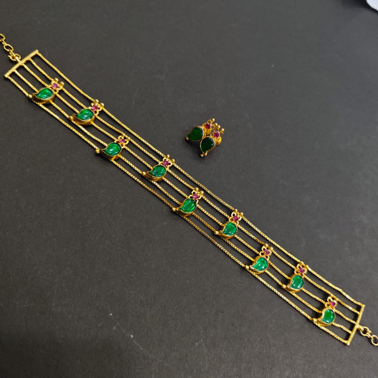 Gold bracelet with green gemstones on a dark surface