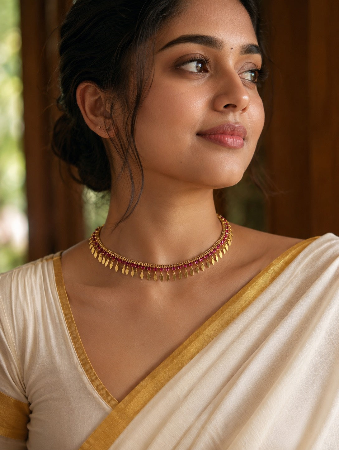 Woman wearing a gold necklace and traditional attire with a blurred background