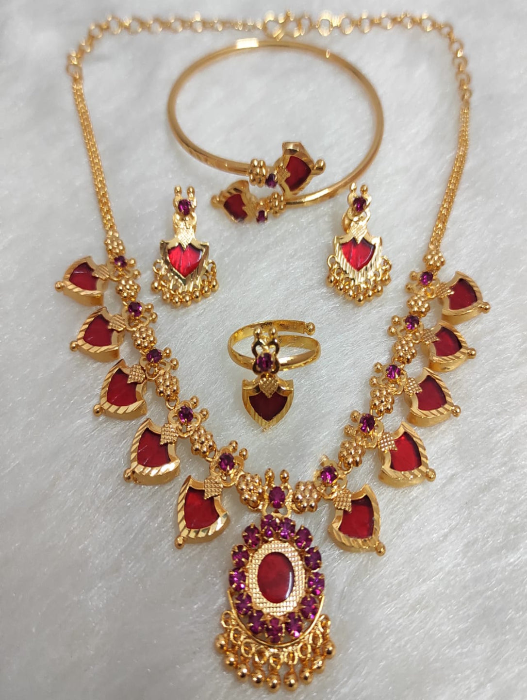 Gold jewelry set with red stones on a white background