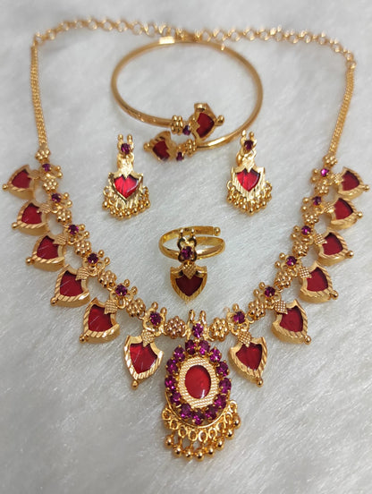 Gold jewelry set with red stones on a light gray background