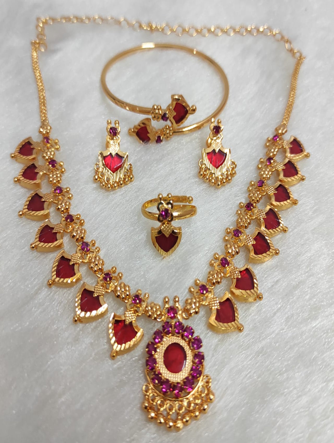 Gold jewelry set with red gemstones on a white background