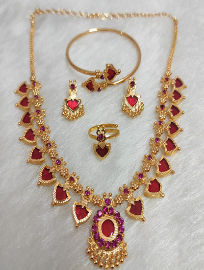 Gold jewelry set with red stones on a light gray background