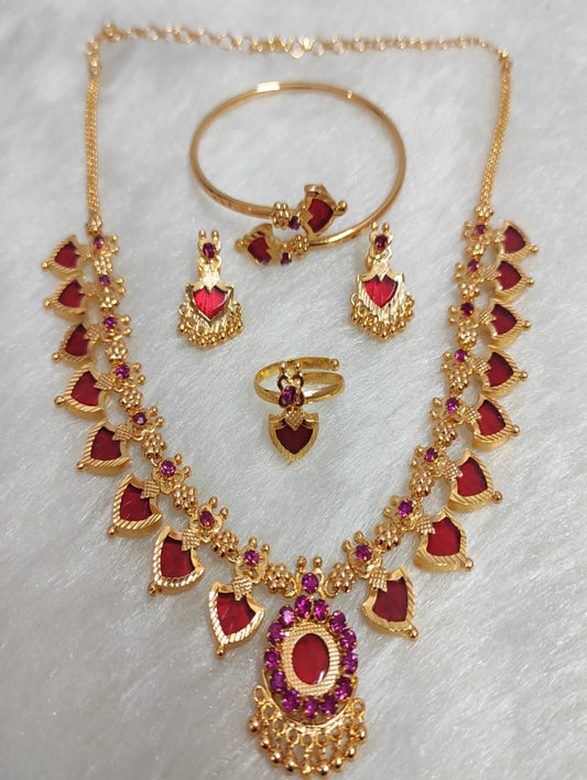Gold jewelry set with red stones on a light gray background